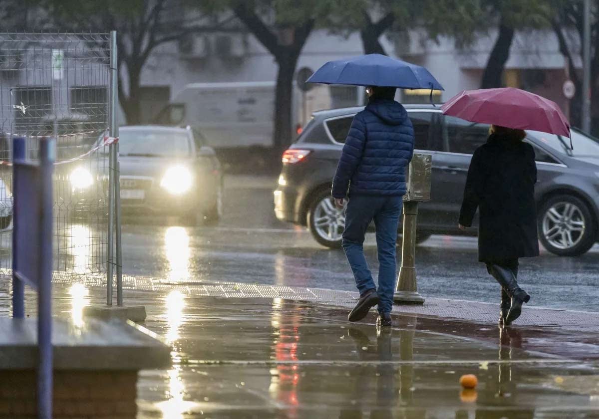 Dos personas se protegen de la lluvia en la capital