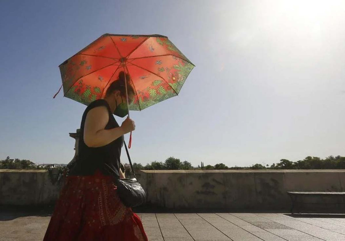 Una mujer se protege del sol con un paraguas