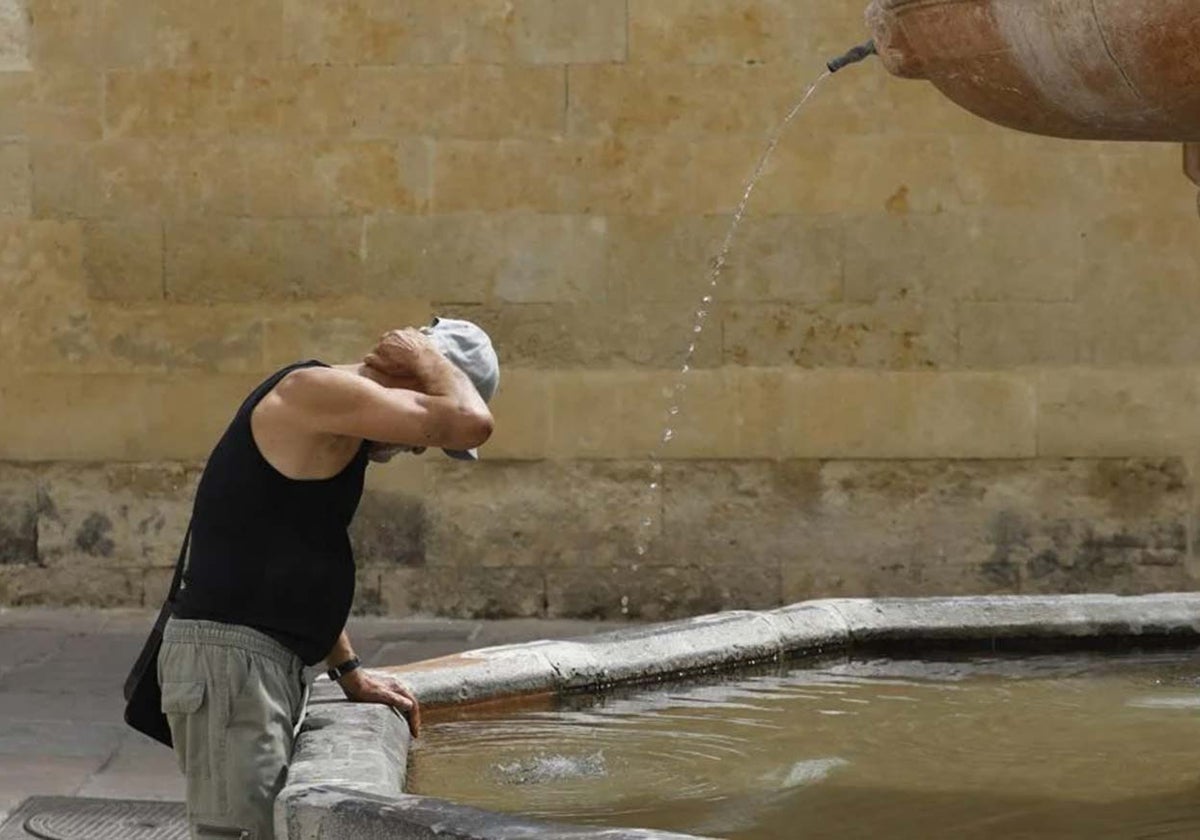 Un hombre se refresca en una fuente