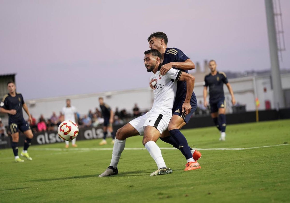 El albiazul Rubén Serrano pugna por el balón con un jugador del conjunto ceutí