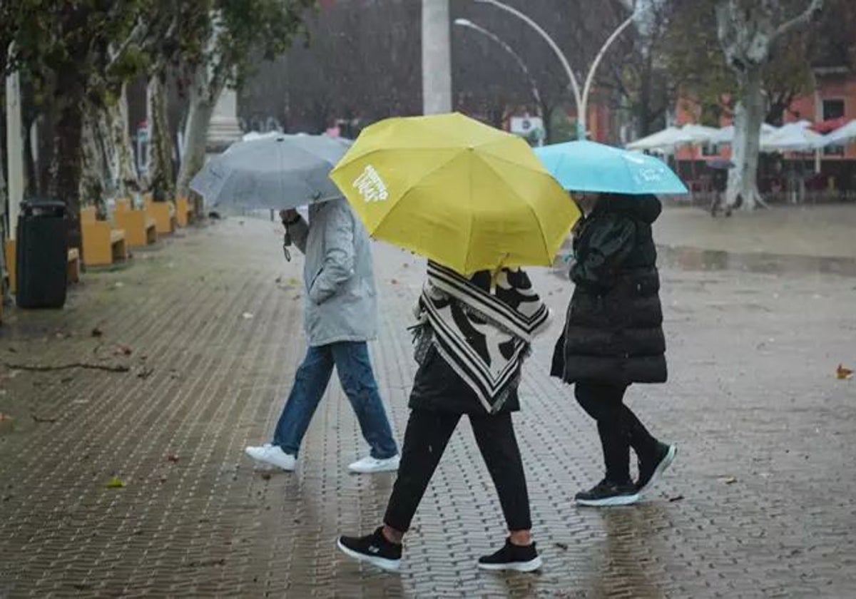 Tres personas, con paraguas bajo la lluvia