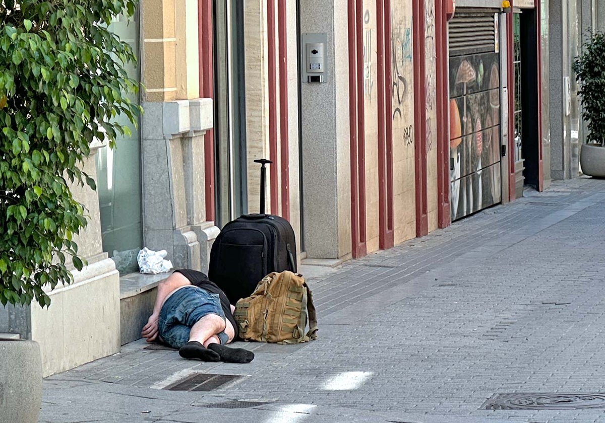 Un hombre durmiendo junto a su equipaje en la plaza Alcalde Coto Mora de la capital