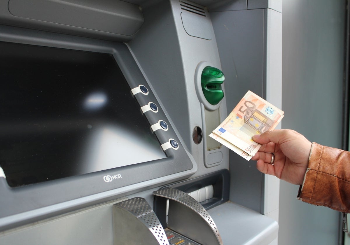 Imagen de archivo de una persona sacando dinero en efectivo de un cajero automático