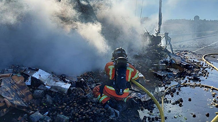 Un bombero sofocando las llamas del camión incendiado