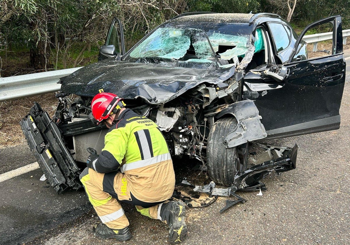 Un bombero junto al coche siniestrado