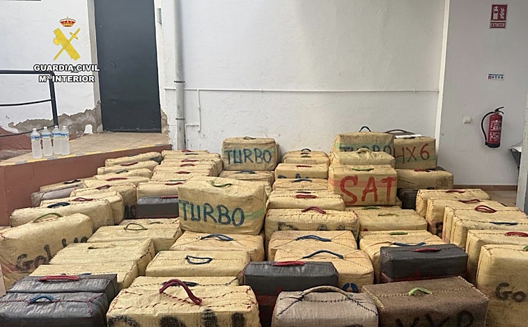 Imagen principal - Alijo de droga intervendio y agentes de la Guardia Civil, durante la operación