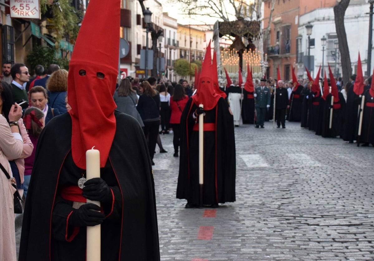 Cortejo de nazarenos de la hermandad del Desconsuelo con el palio al fondo