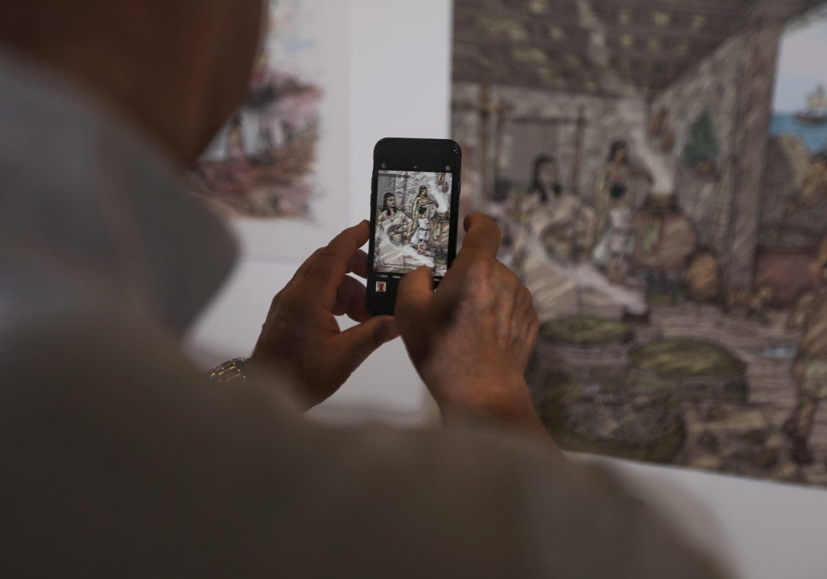 Una de las personas asistentes a la inauguración de esta muestra fotografía una ilustración.