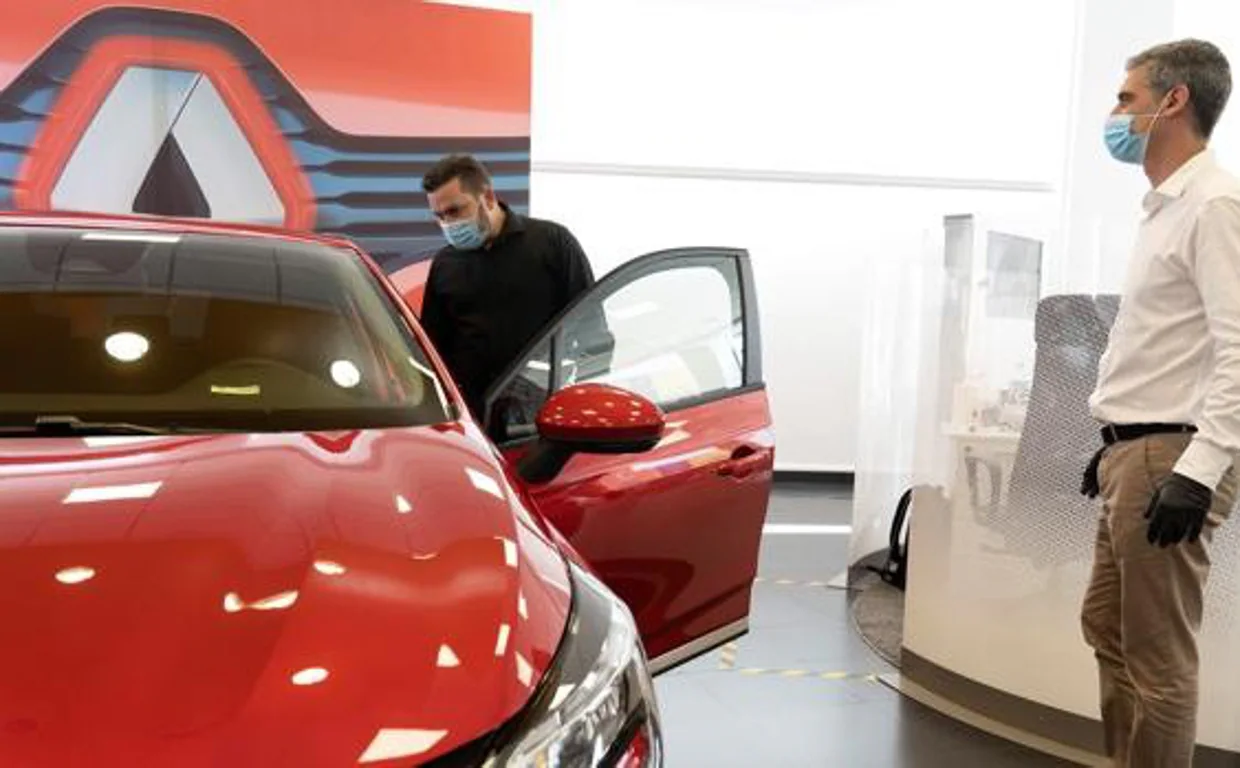 Un potencial comprador prueba un coche en el concesionario de Renault ante la mirada del vendedor