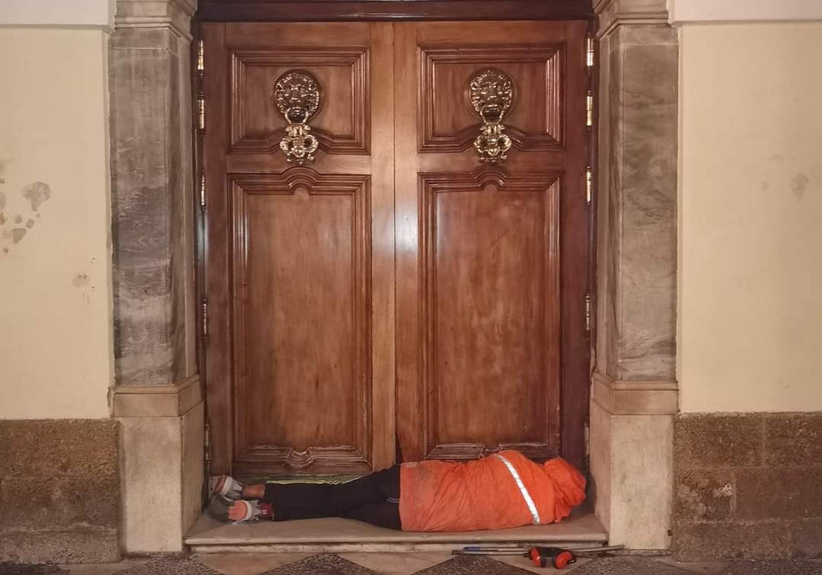 Una persona sin hogar durmiendo en la misma puerta del Ayuntamiento de Cádiz para refugiarse del frío y la lluvia.