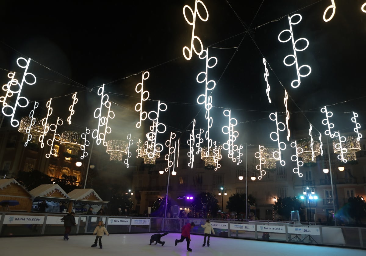 Unos niños juegan en la pista de hielo instalada en la plaza de San Antonio de la capital, bajo la iluminación típica navideña.