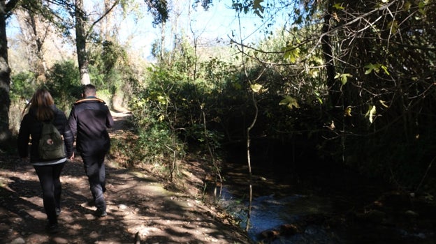 Dos caminantes pasean por la orilla del río Majaceite.