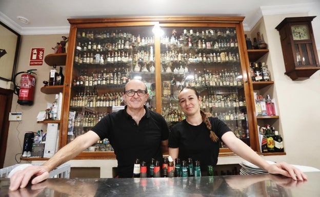 Carlos y su hija María, con la vitrina de la colección de botellines detrás.