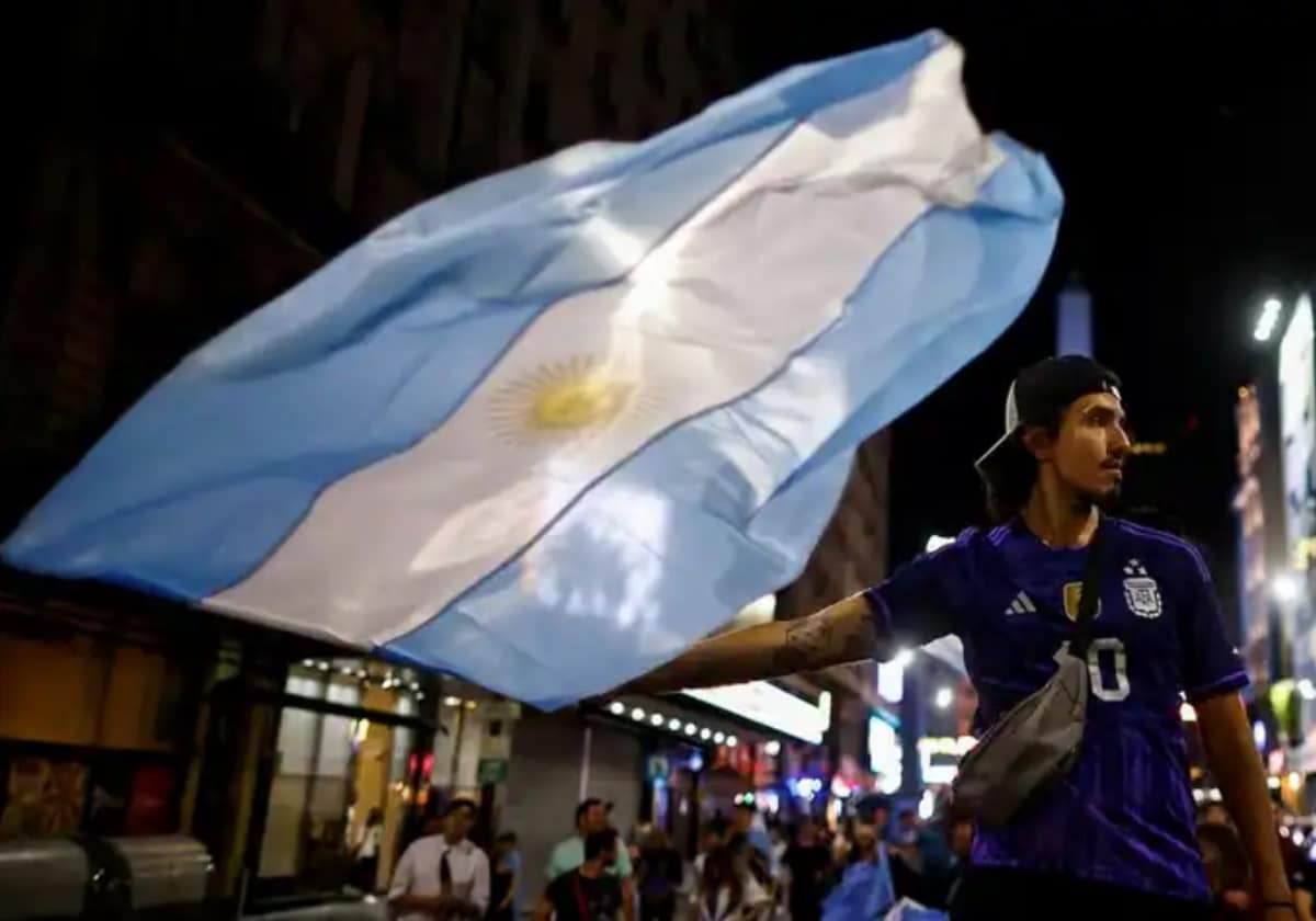 Un joven celebra con una bandera argentina la victoria de Milei.