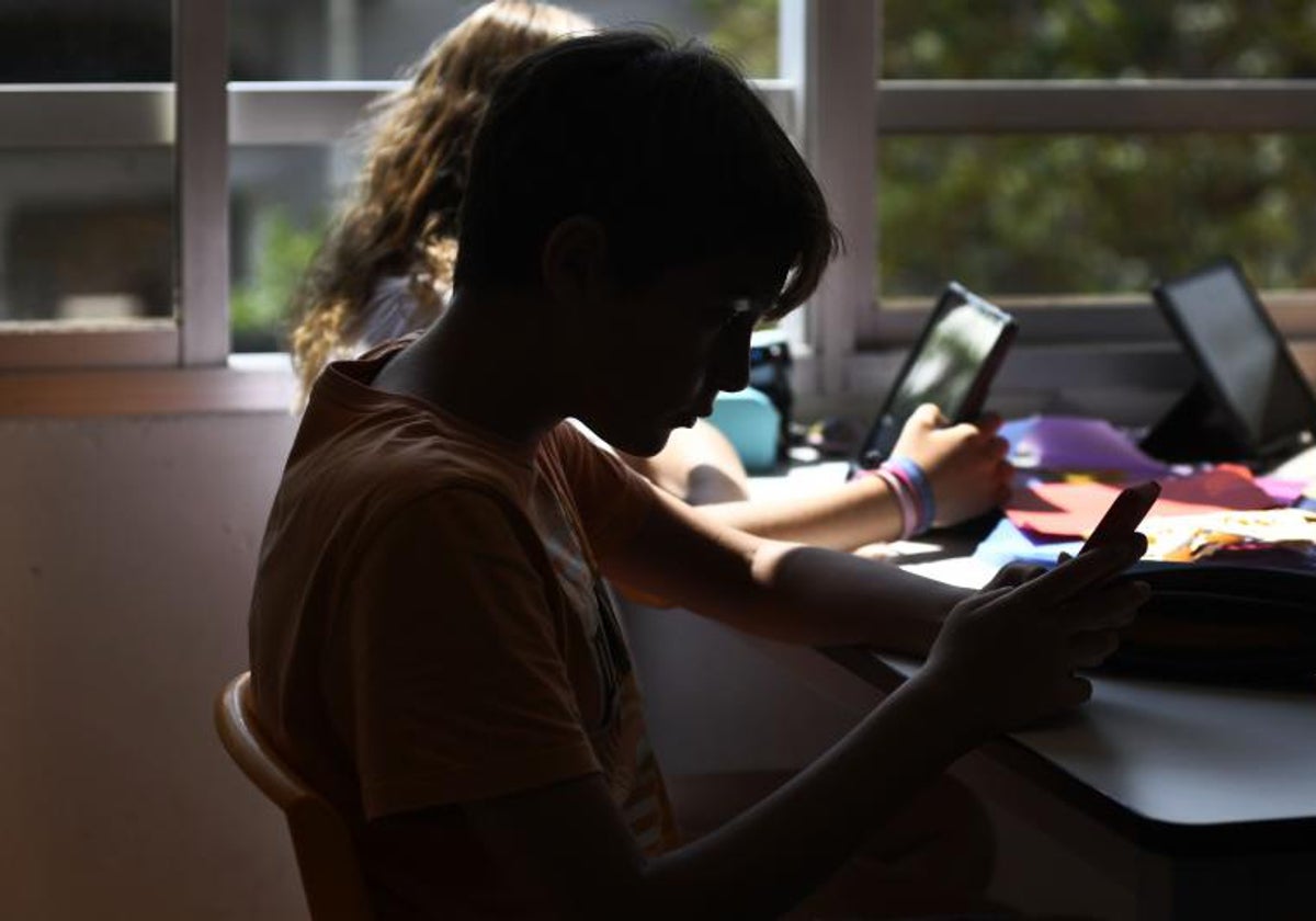 Un joven hace uso de un dispositivo móvil en el aula.