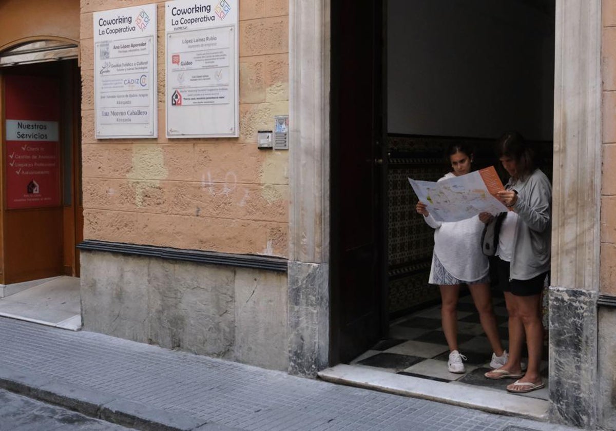 Turistas observando un plano de Cádiz en una casapuerta.