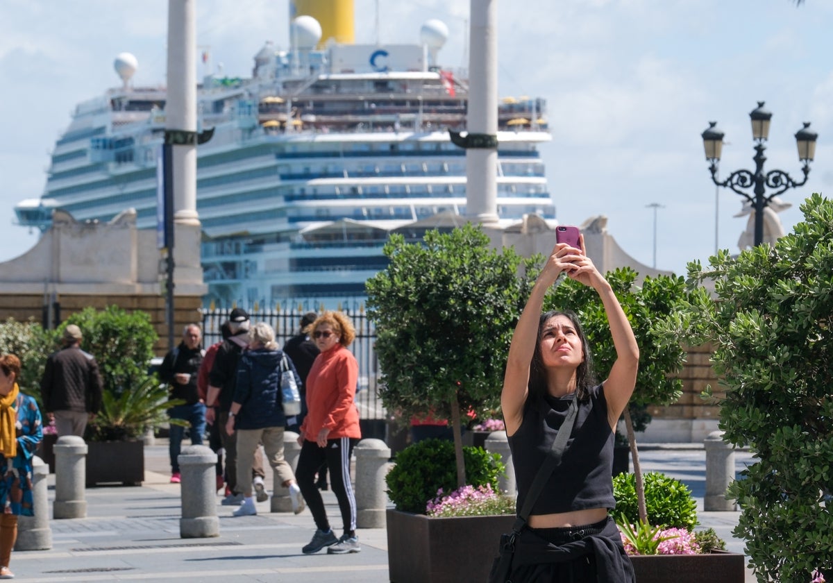 Una turista fotografía la ciudad con un crucero al fondo.