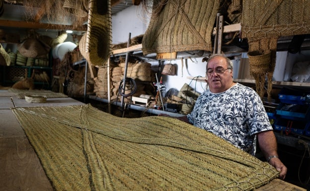 Terminando de coser una persiana de esparto.