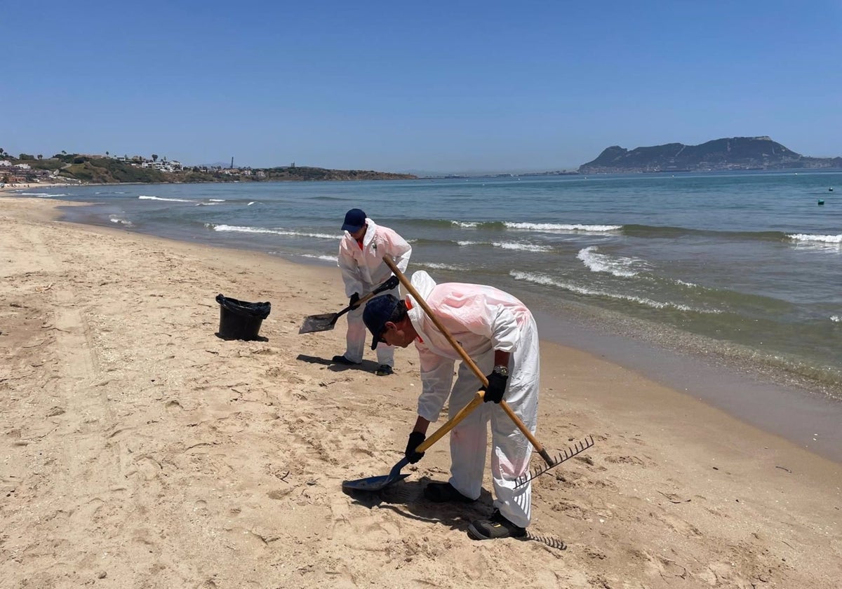 Personal del servicio de limpieza y mantenimiento de playas de Algeciras retira el vertido de fuel de la playa de Getares.