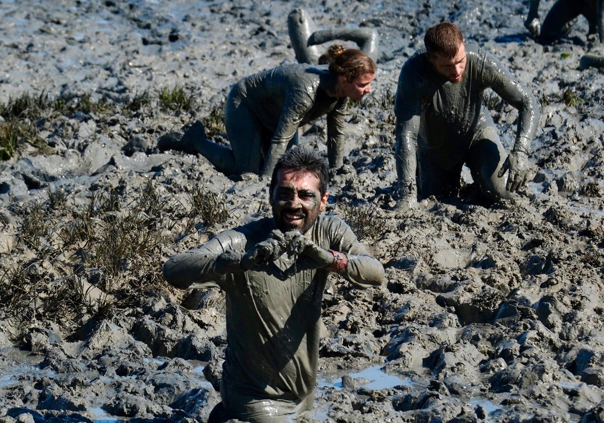 Tres participantes de esfuerzan sobre el barro.