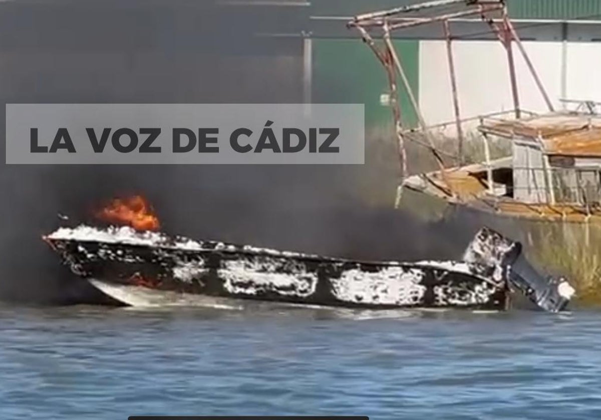 La lancha ya casi calcinada en la margen del río Guadalquivir.