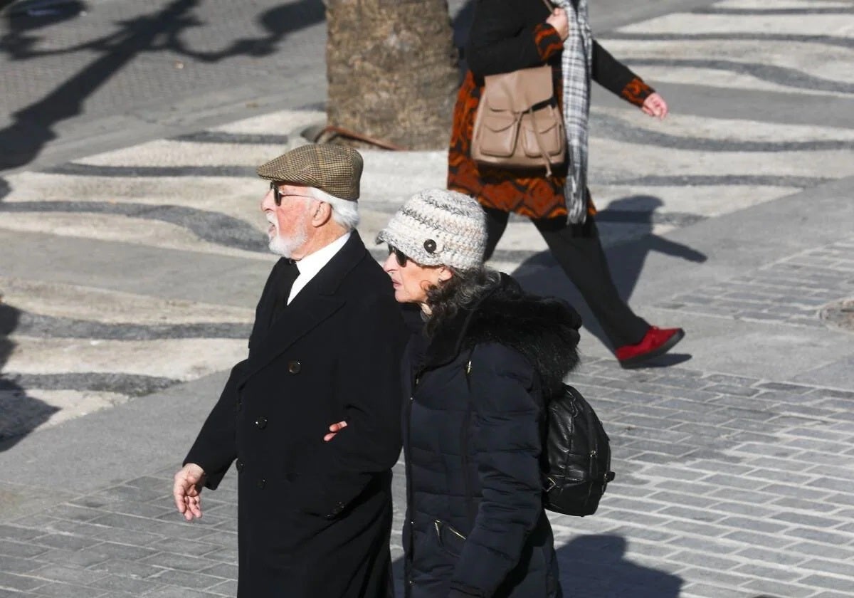 Una pareja abrigada paseando por la capital gaditana