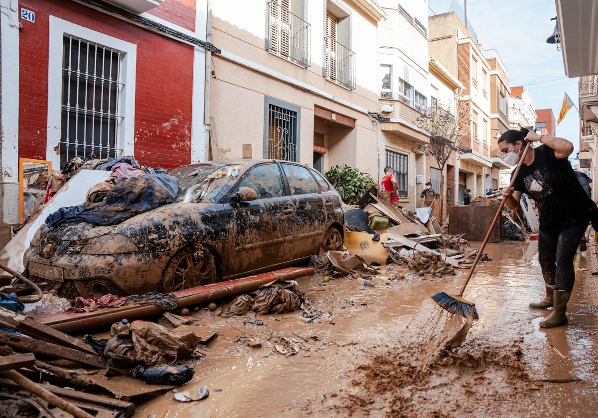 Una persona trata de limpiar el lodo en Catarroja, Valencia.