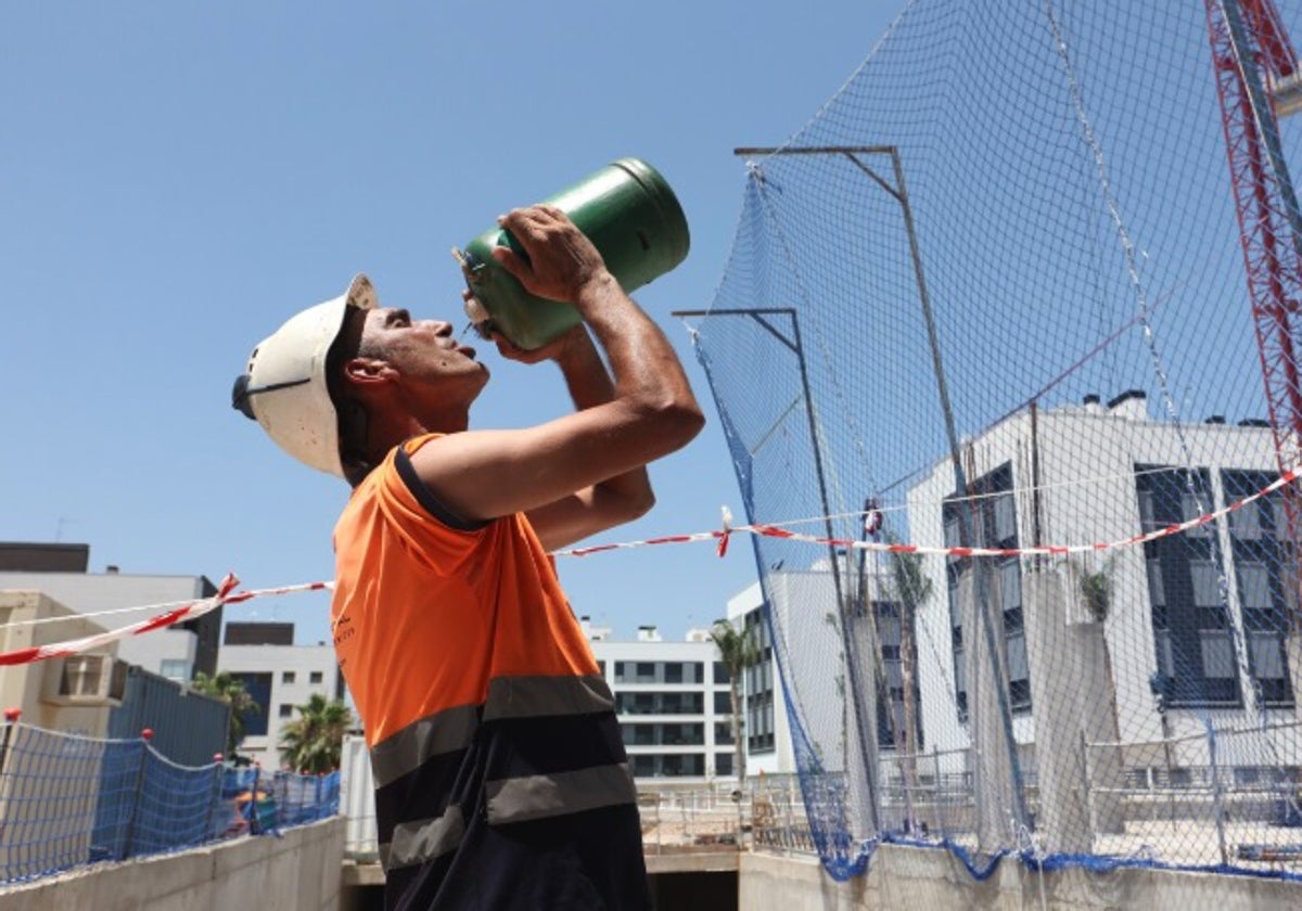 Un trabajador de la construcción hidratándose mientras trabaja, en foto de archivo.