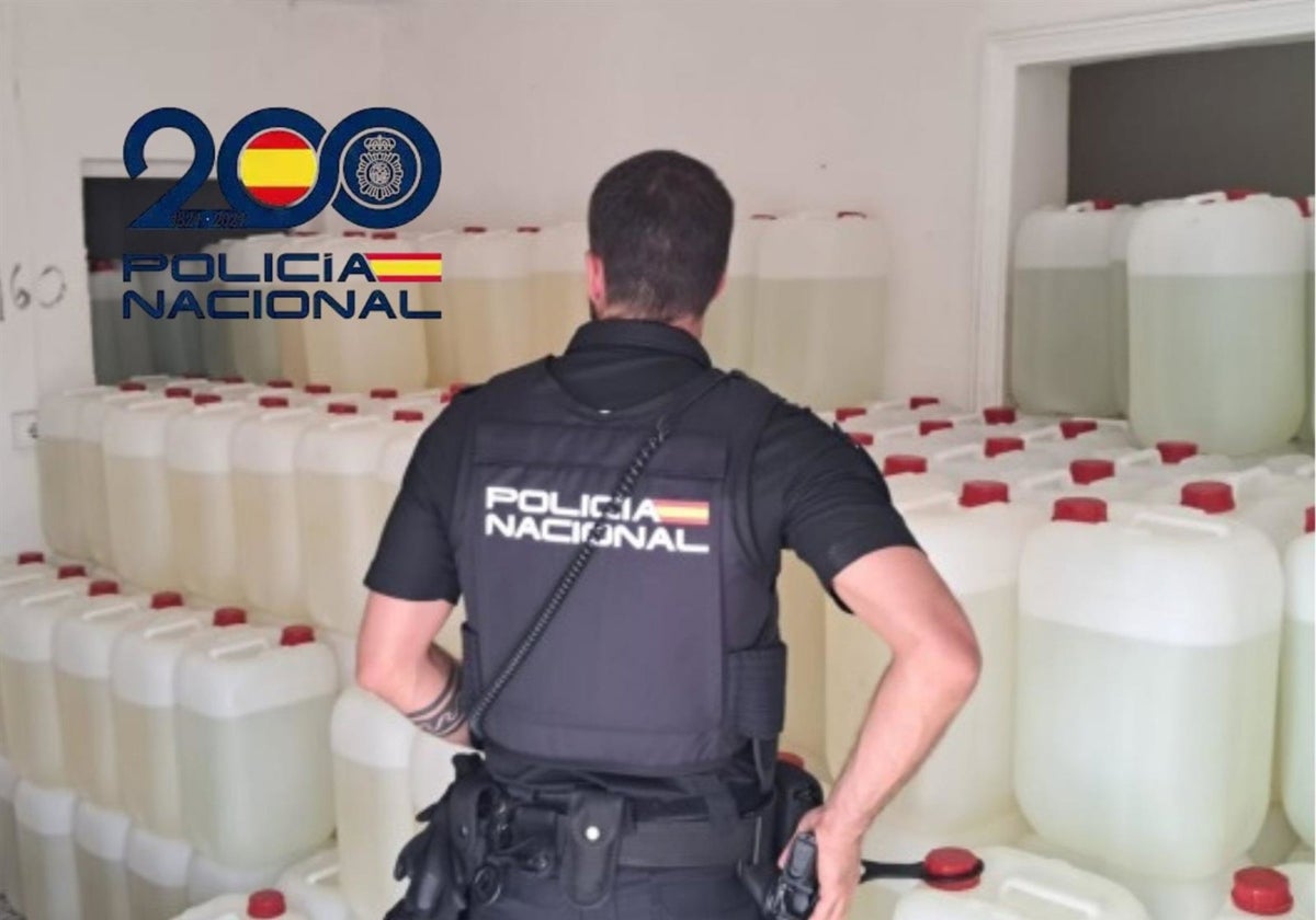 Un agente de la Policía Nacional con las garrafas con combustible para narcolanchas intervenidas en El Puerto