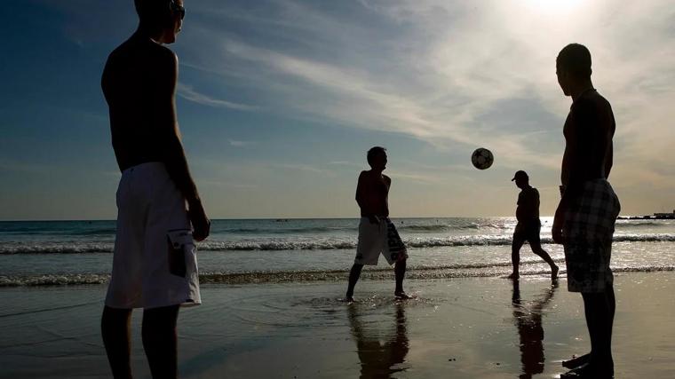 Imagen de unos jóvenes jugando a la pelota en una playa de Cádiz
