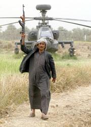 Un hombre iraquí exhibe su AK-47 ante un helicóptero Apache de los Estados Unidos, capturado por el Ejército de Sadam en Hindiya, 120 kilómetros al sur de Bagdad. REUTERS