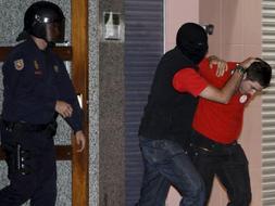 Efectivos de la Policia Nacional trasladan a uno de los cuatro jóvenes detenidos en Pamplona el lunes y que hoy han ingresado en prisión por orden del juez Marlaska. /Efe
