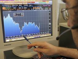 Una persona señala con el bolígrafo la evolución del Ibex 35 en una pantalla, hoy. /Efe