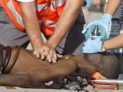 Dos miembros de la Cruz Roja realizan un masaje cardiaco a uno de los 136 inmigrantes que han llegado al puerto de los Cristianos de Tenerife. /Efe