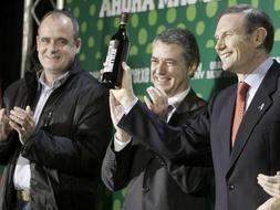 El lehendakari y candidato a la reelección por el PNV, Juan José Ibarretxe, acompañado por el presidente del partido, Íñigo Urkullu (c), y el portavoz, Joseba Egibar (i), enseña una botella de vino 'Viña Ibarretxe' obsequiado por su compañero de lista Mikel Martínez, durante el acto de inicio de campaña. /Efe