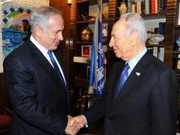 El presidente de Israel, Simón Peres, estrecha la mano al líder del Likud, Benjamin Netanyahu. /Reuters