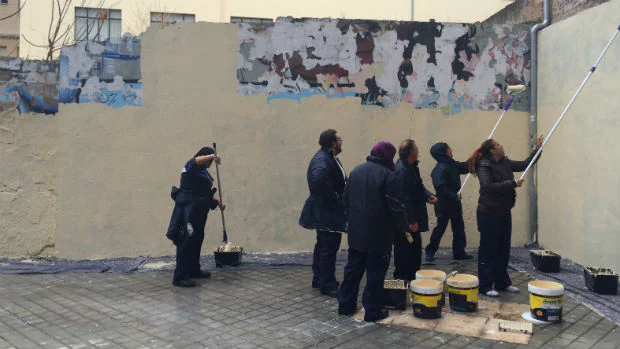 Desempleados limpian pintadas en la trasera del edificio de Hermanitas de los Pobres de Granada