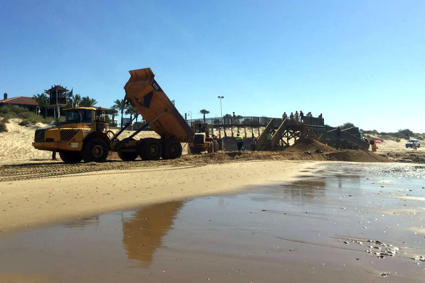 Un camión depositando arena en la playa de Islantilla