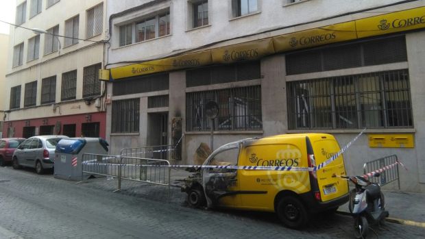 Estado en el que ha quedo el coche de Correos y daños en la fachada del edificio