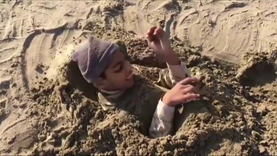 Varios hombres se entierran en una playa de Pakistán durante el eclipse solar