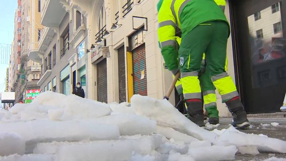 Servicios de limpieza retiran la nieve acumulada en la Gran Vía de Madrid