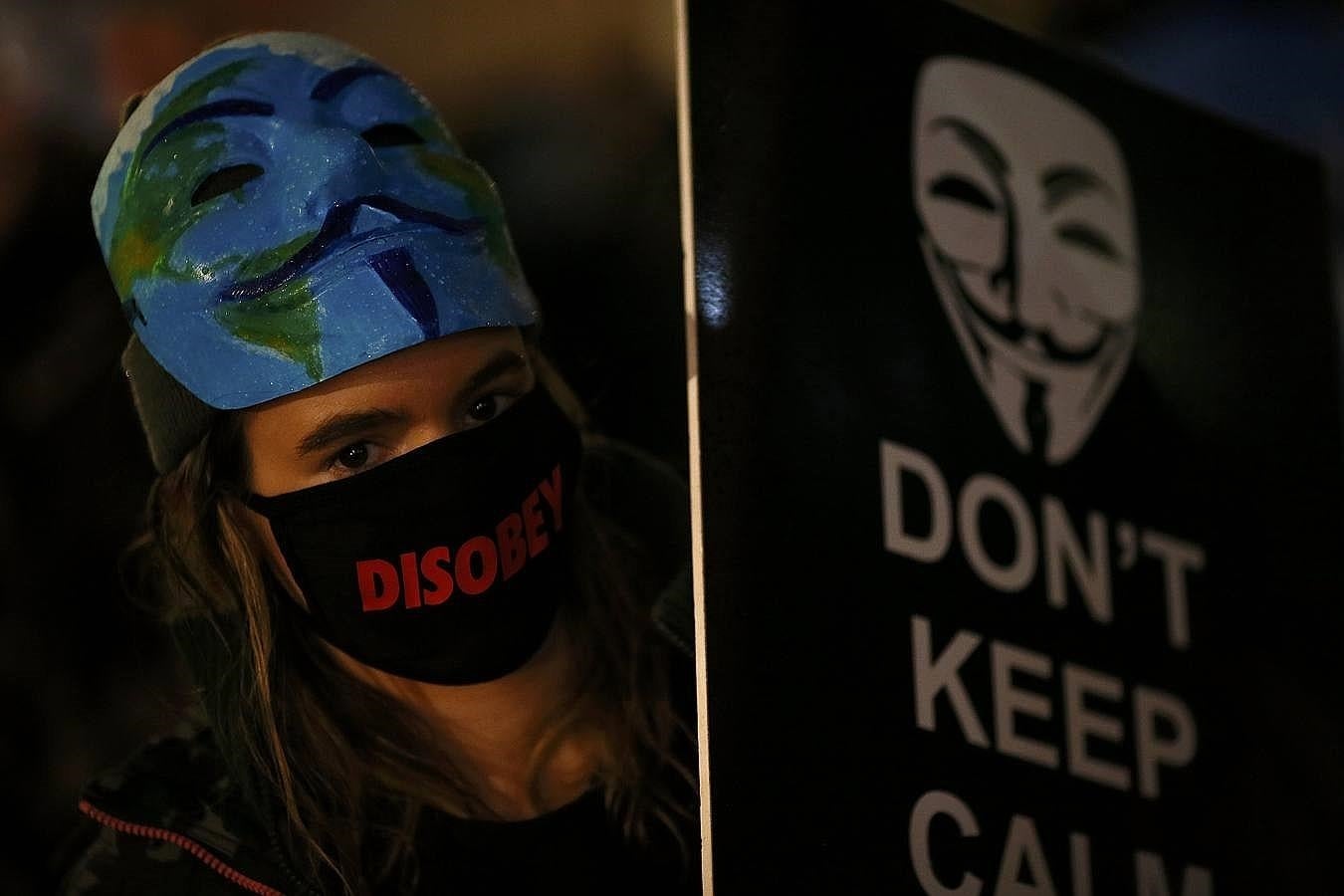 Una simpatizante de «Anonymous», con el rostro tapado, lleva una pancarta durante la manifestación de Londres. 