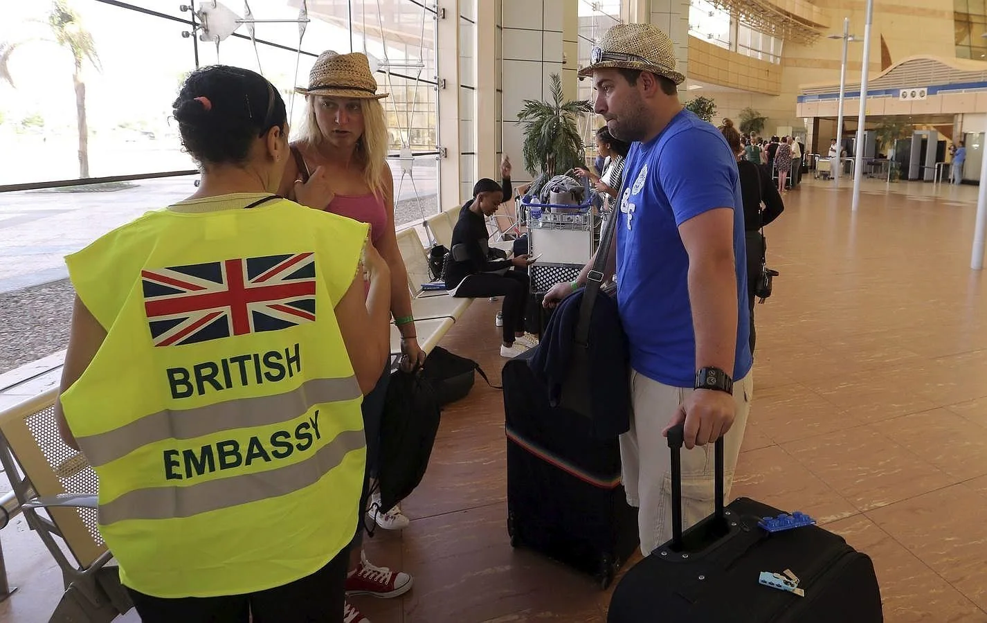 Una empleada de la embajada británica conversa con dos turistas en el aeropuerto de Sharm el-Sheij