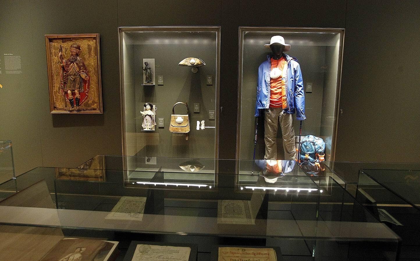La característica indumentaria del peregrino de la actualidad se musealiza junto a prendas de siglos anteriores