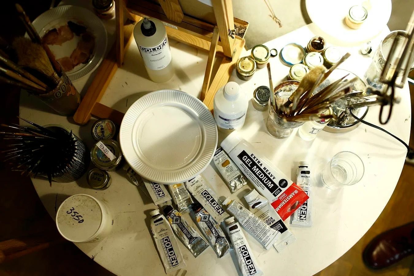 La mesa del comedor, llenade pinceles y tubos de pintura, hace las veces de mesa de trabajo 