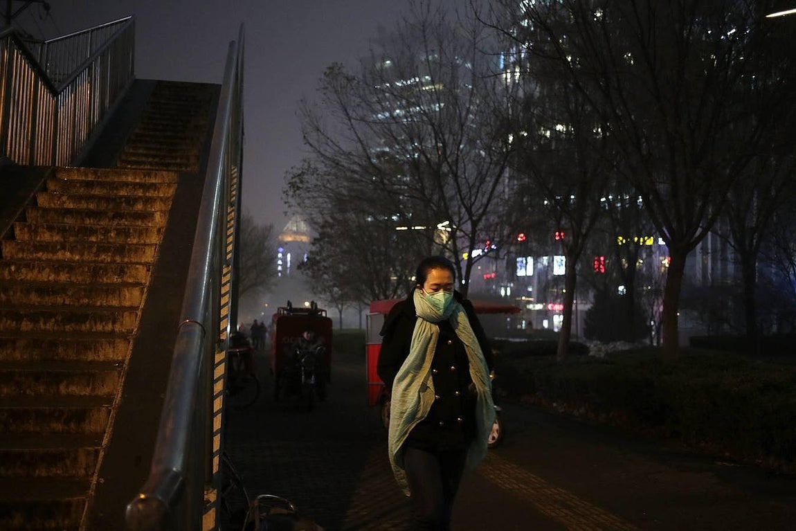 Una mujer pasea por las calles de Pekín con una mascarilla