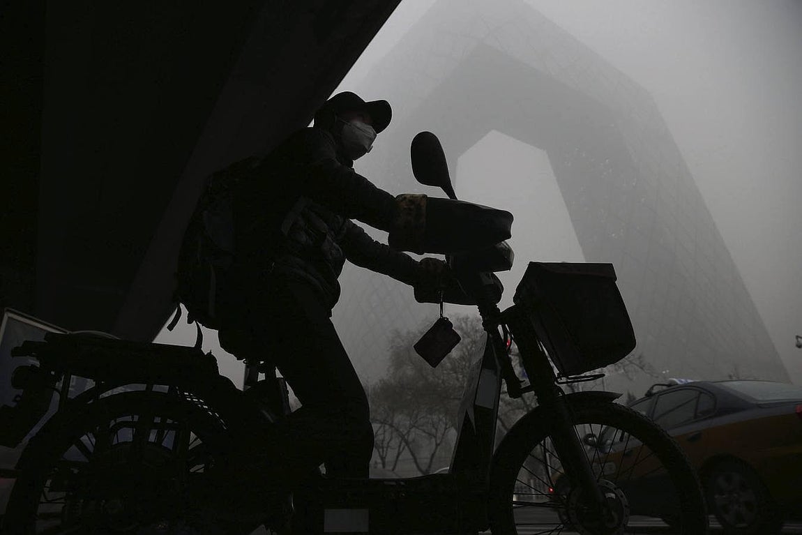 Un hombre circula en moto por las calles de Pekín