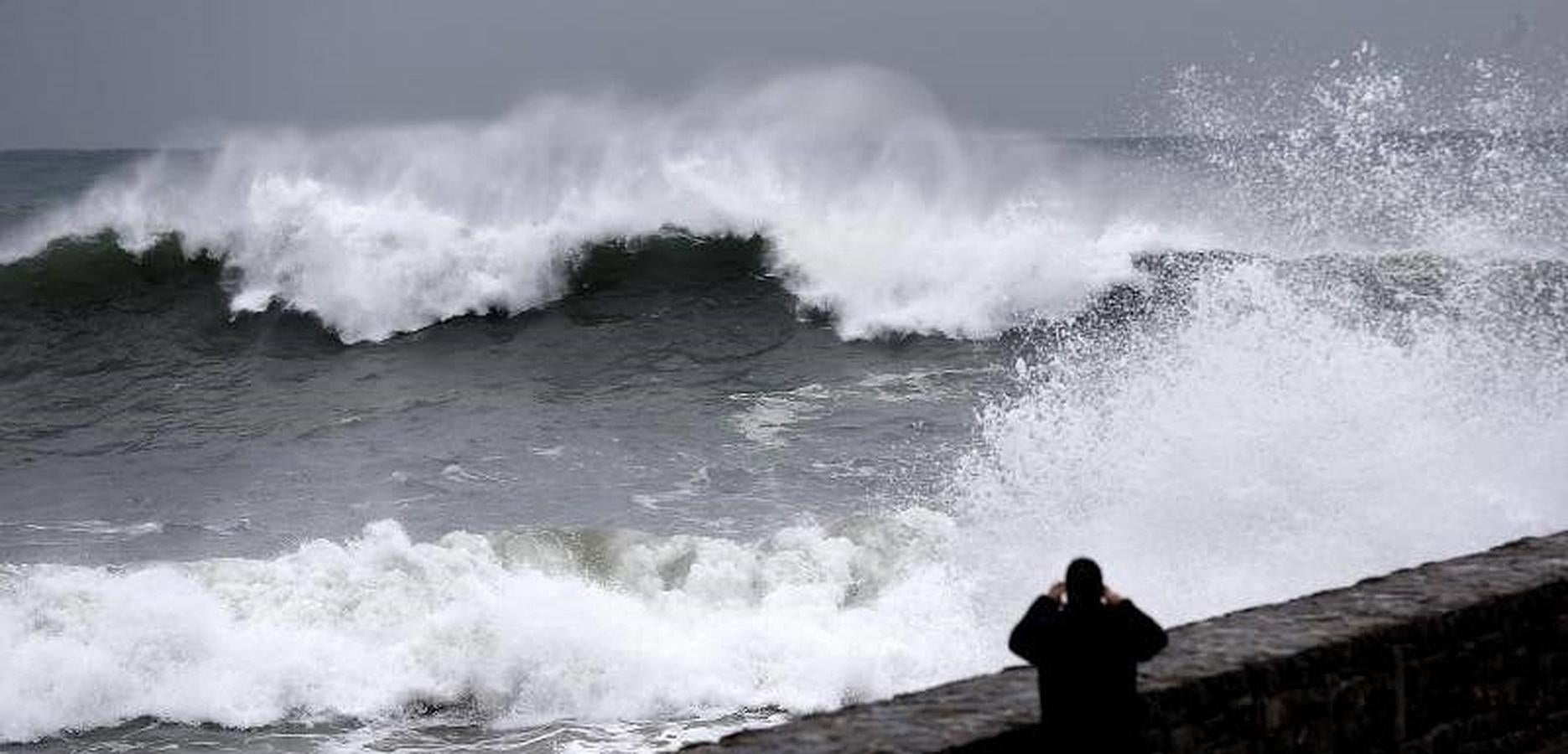 Un hombre fotografía una ola en el paseo de La Zurriola de San Sebastián