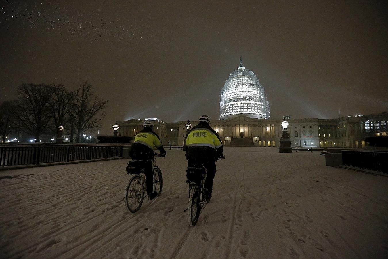 La tormenta de nieve «Jonas» altera la rutina en Washington. Dos policías transitan en bicicleta por los alrededores del Capitolio