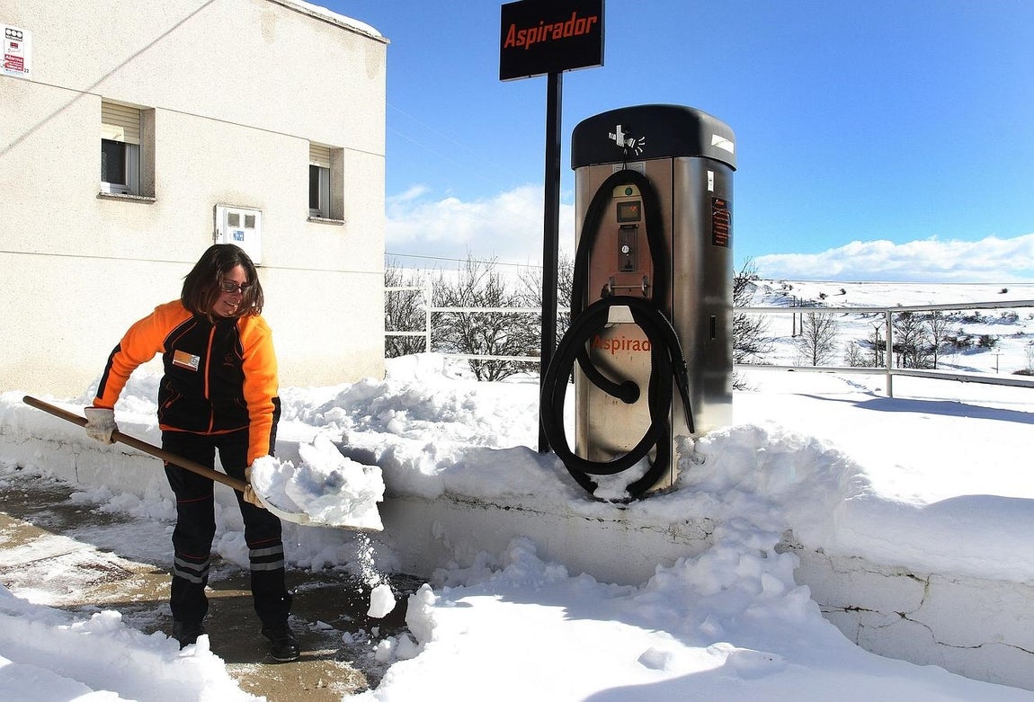 Una operaria de una estación de servicio de Santibañez de la Peña (Palencia) retira la nieve acumulada. 